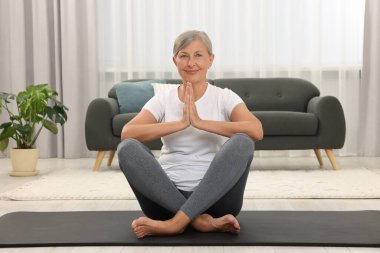 Mutlu son sınıf öğrencisi kadın evde yoga yapıyor.