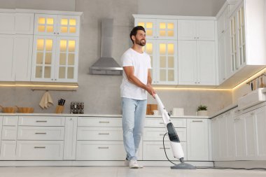 Mutfak paspası ile yerleri temizleyen mutlu bir adam. Düşük açılı.