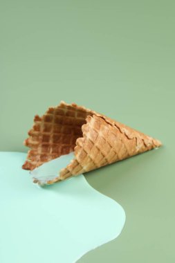 Eritilmiş dondurma ve yeşil arka planda gofret konisi, yakın plan.