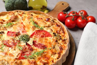 Lezzetli peynirli kiş ve açık gri masadaki malzemeler. Yakın plan.