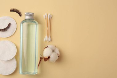 Makyaj temizleyicisi, pamuk çiçeği, pedler, bezler ve sarı arka planda takma kirpikler. Metin için boşluk