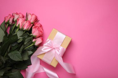 Hediye kutusu ve pembe arka planda güzel çiçekler. Metin için boşluk