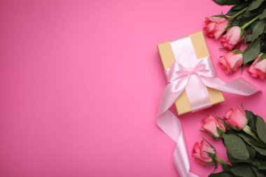 Hediye kutusu ve pembe arka planda güzel çiçekler. Metin için boşluk