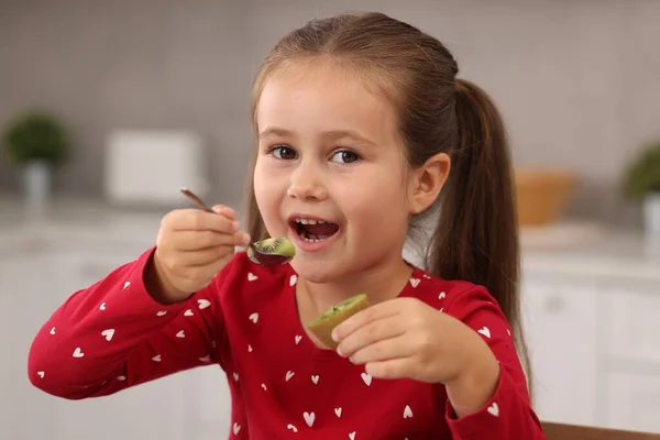 かわいい女の子は屋内でおいしい新鮮なキウイを食べる — ストック写真