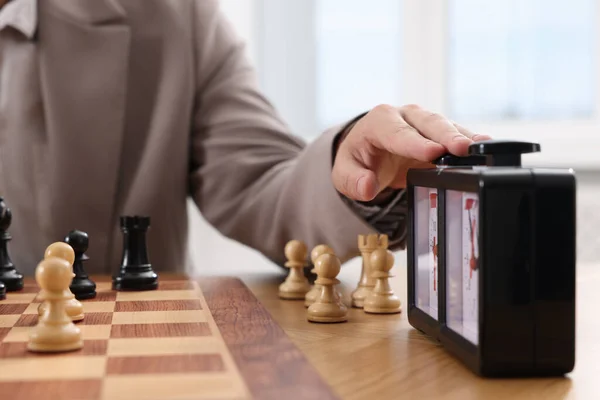 Man turning on chess clock during tournament at table, closeup