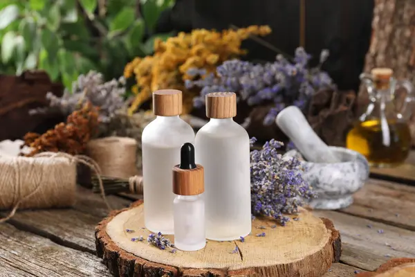Bottles of essential oils and dry lavender flowers on wooden table. Medicinal herbs
