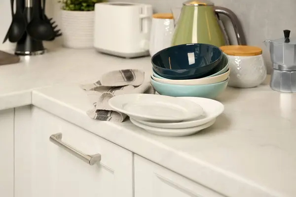 Set of clean color bowls and plates on white countertop in kitchen