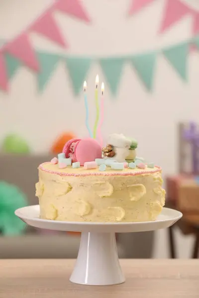 Delicious cake decorated with macarons and marshmallows on wooden table against blurred background
