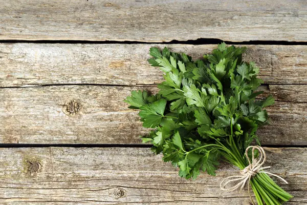 Bunch of fresh green parsley leaves on wooden table, top view. Space for text