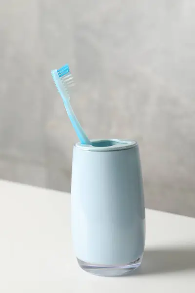 Plastic toothbrush in holder on white countertop