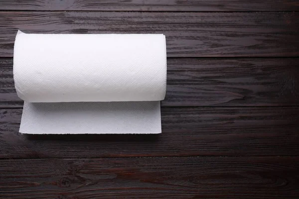 Roll of tissue towels on wooden table, top view. Space for text