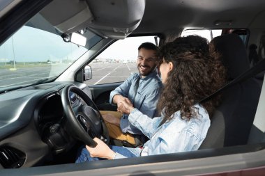 Ehliyet kursu. Otoparkta ders sırasında sürücü eğitmeniyle tokalaşan mutlu öğrenci.