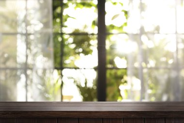 Boş ahşap masa pencerenin önünde, içi bulanık. Tasarım için boşluk