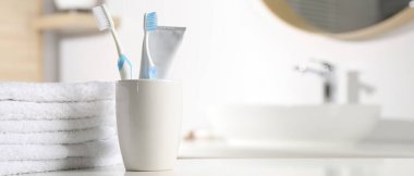 Plastik diş fırçaları, diş macunu ve havlular banyoda beyaz masada, mesaj için yer var. Pankart tasarımı