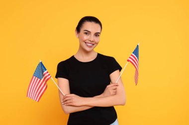 4 Temmuz - ABD 'nin Bağımsızlık Günü. Sarı arka planda Amerikan bayrakları olan mutlu kadın.