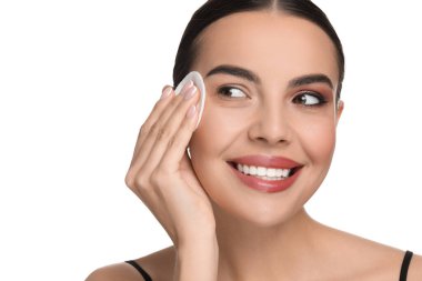 Güzel bir kadın beyaz arka planda pamuk yastıkla makyajı kaldırıyor.