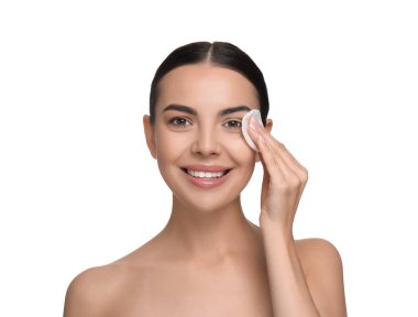 Güzel bir kadın beyaz arka planda pamuk yastıkla makyajı kaldırıyor.