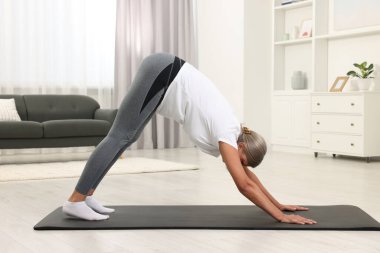 Son sınıf öğrencisi kadın evde yoga yapıyor.