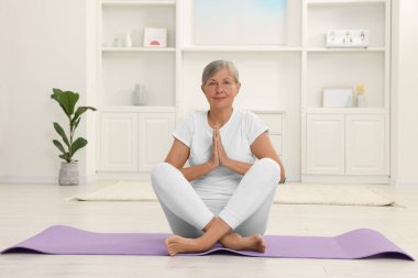 Son sınıf öğrencisi kadın evde yoga yapıyor.
