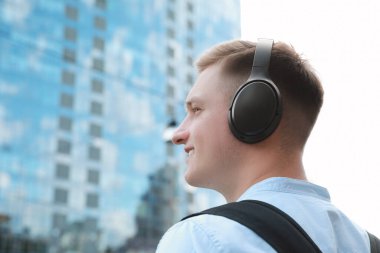 Kulaklıklı gülen adam dışarıda müzik dinliyor. Metin için boşluk
