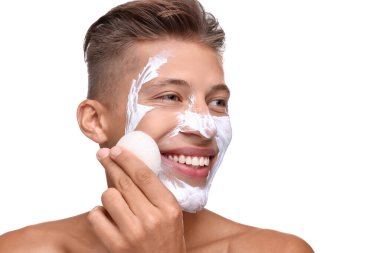 Mutlu genç adam maskesini beyaz arka planda süngerle yıkıyor.