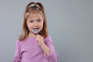 Açık gri arka planda lolipopu olan hoş bir kızın portresi. Metin için boşluk