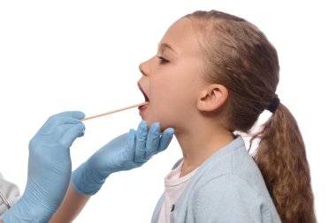 Doktor, beyaz arka planda dil bastırıcı ile kızın ağız boşluğunu inceliyor.