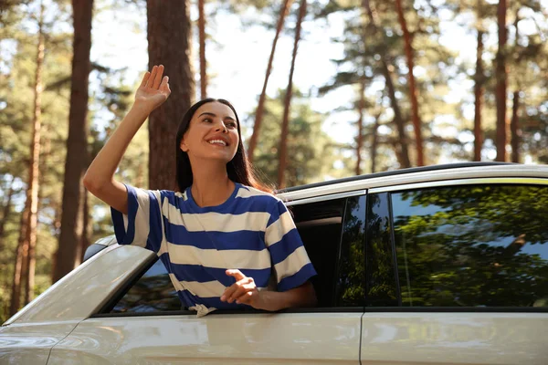 Enjoying trip. Happy young woman leaning out of car window, low angle view