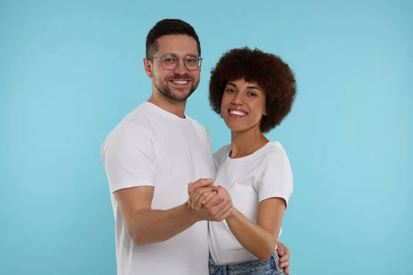 International dating. Happy couple dancing on light blue background