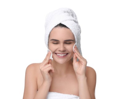 Beyaz arka planda pamukla yüzünü temizleyen genç bir kadın.