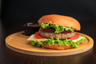 Sebzeli lezzetli burger, ahşap masada köfte ve peynir, yakın plan.