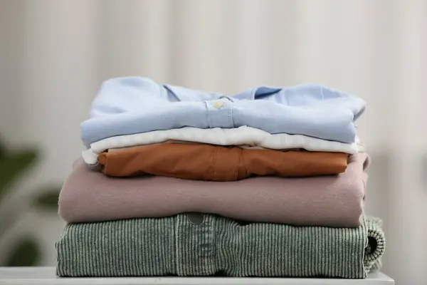 Stack of different folded clothes white on table, closeup