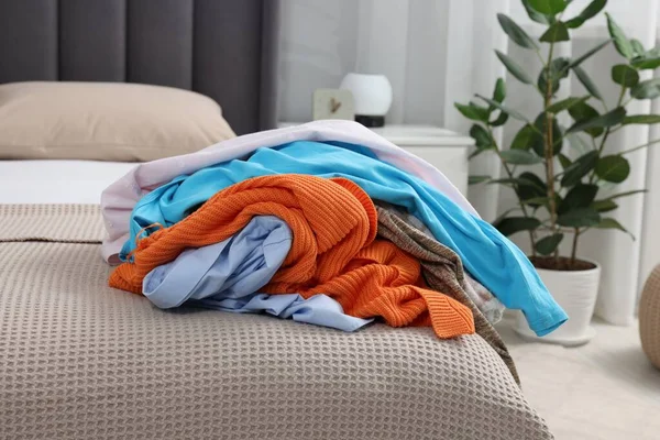 Pile of different clothes on bed at home