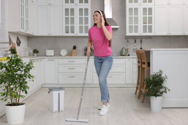 Temizliğin tadını çıkarıyorum. Kulaklıklı mutlu kadın müzik dinliyor ve mutfakta yerleri paspaslıyor.