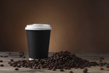 Paket kahve. Kağıt bardak ve kavrulmuş fasulye ahşap masada, metin için yer var.