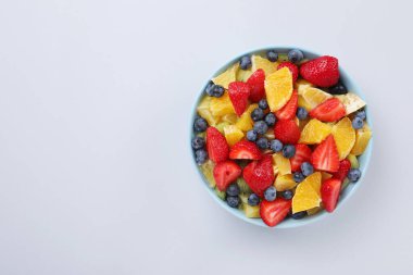 Açık gri arka planda, kasede lezzetli meyve salatası, üst manzara. Metin için boşluk