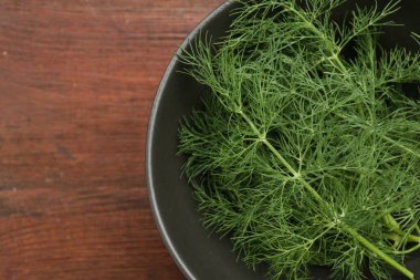 Bir kase taze dereotu ahşap masada, üst manzara. Metin için boşluk