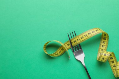 Yeşil arkaplanda ölçüm bandı olan çatal, metin için boşluk olan üst görünüm. Diyet kavramı