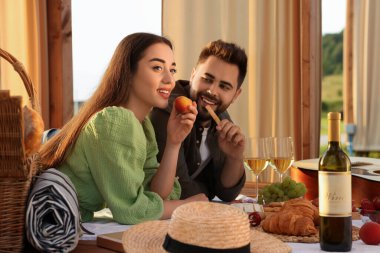 Romantik bir randevu. Güzel bir çift, ahşap çardakta piknik yapıyor.