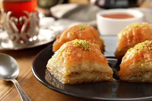 Delicious sweet baklava with pistachios on wooden table, closeup