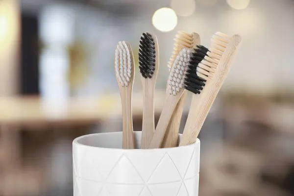Bamboo toothbrushes in holder against blurred background, closeup