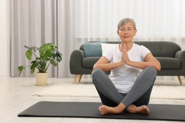 Son sınıf öğrencisi kadın evde yoga yapıyor.