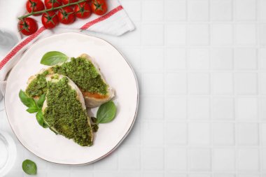 Pesto soslu leziz tavuk göğsü, fesleğen ve domatesler beyaz fayanslı masa, düz yatak. Metin için boşluk