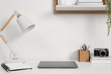Merkez ofis. Laptop, klasik kamera, lamba ve kırtasiye malzemeleri beyaz masa içinde.