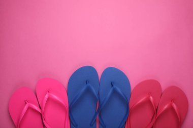 Pembe arka planda farklı tarz parmak arası terlikler, düz yatış. Metin için boşluk