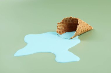 Eritilmiş dondurma ve yeşil arka planda gofret konisi, yakın plan.