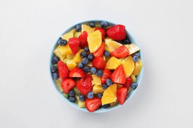 Açık gri arka planda, kasede lezzetli meyve salatası, üst manzara.