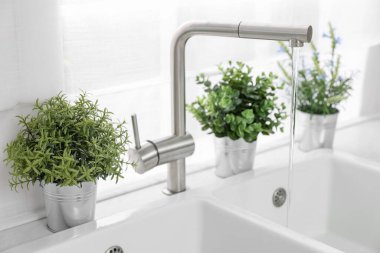 Mutfaktaki tezgahta farklı saksıda suni bitkiler var. Ev dekoru