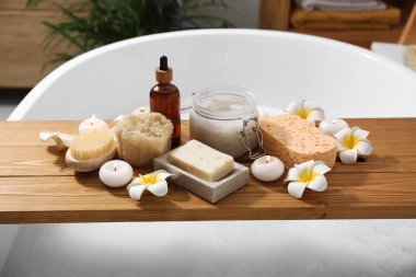 Farklı spa ürünleri ve banyodaki küvet tepsisindeki güzel çiçeklerle kompozisyon.