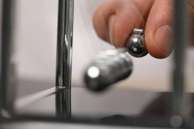 Newton 'un beşiğiyle oynayan adam, yakın plan. Enerji korunumunun fizik yasası